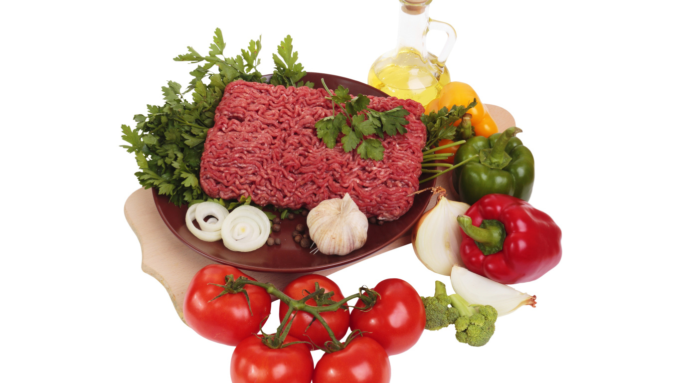 Minced meat on a white plate with vegetables and herbs