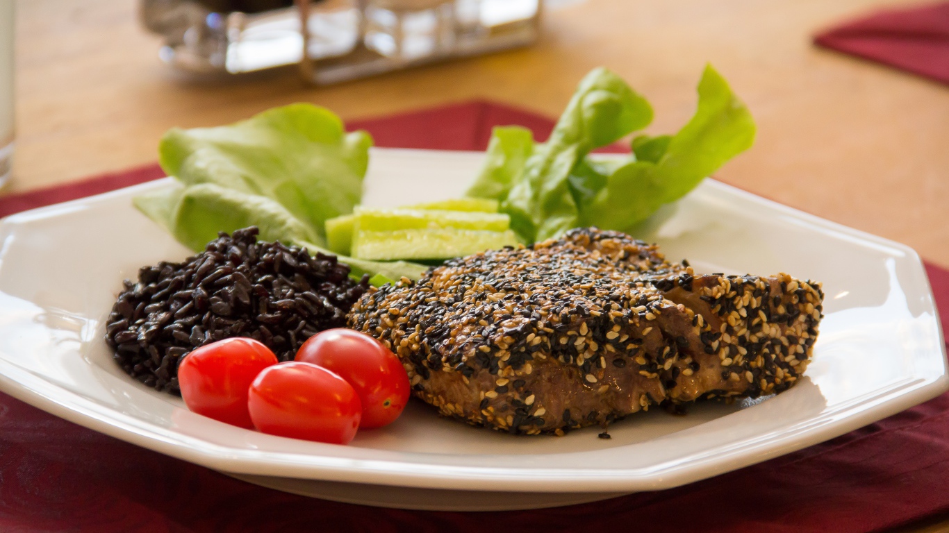 Кусок мяса на тарелке с рисом и овощами 