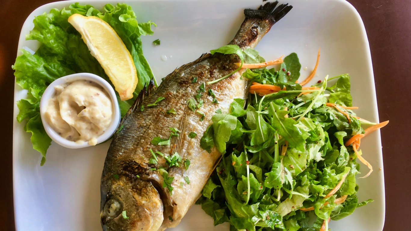 Жареный карась на тарелке с салатом 