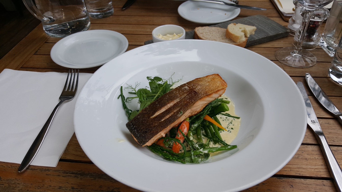 Кусок красной рыбы с овощами на столе в ресторане