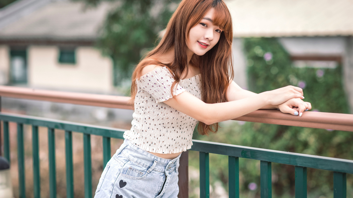 Красивая девушка азиатка стоит у перил у дома