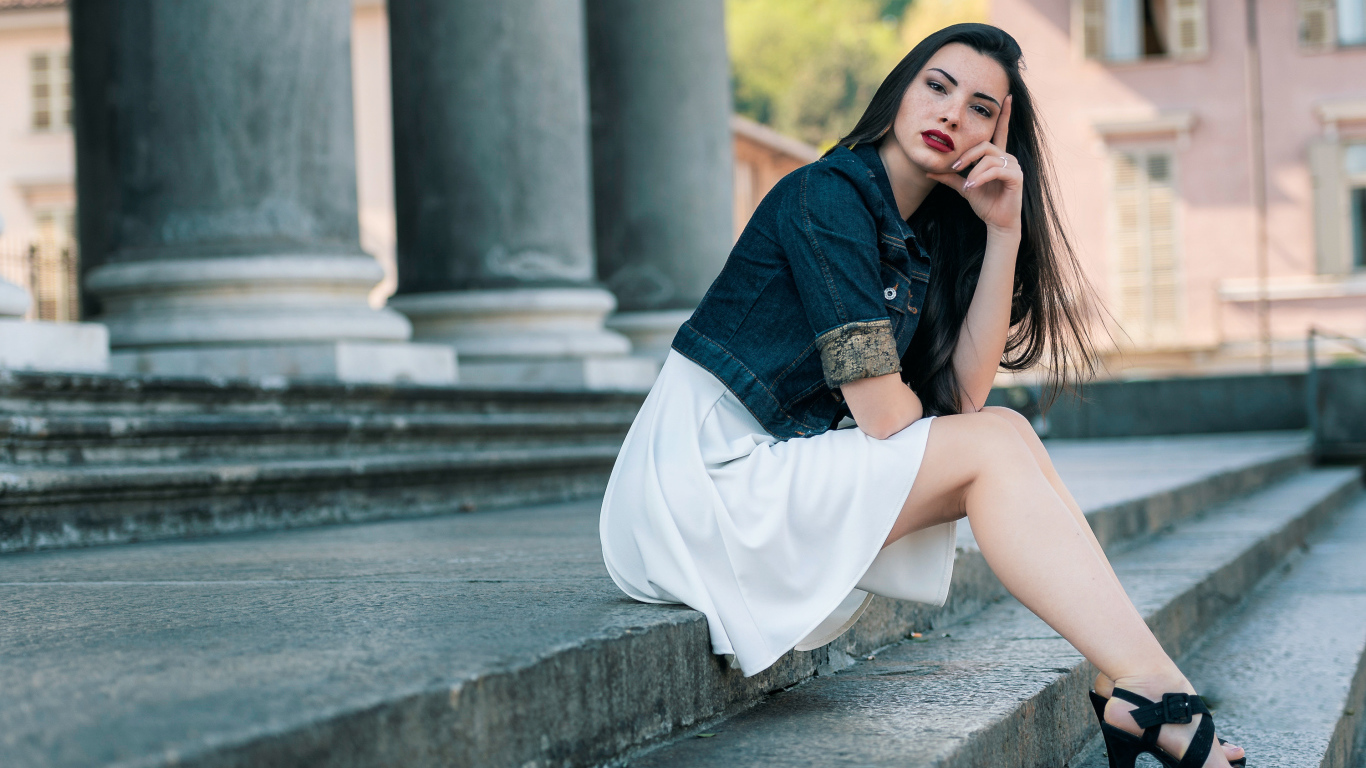 Девушка в белом платье сидит на ступеньках