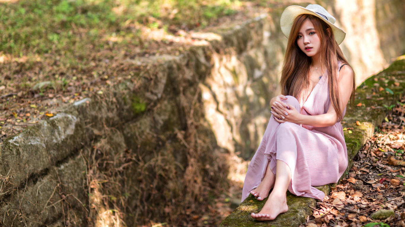 Девушка азиатка в розовом платье сидит на земле