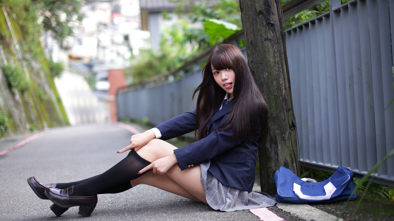 Девушка азиатка в черных чулках сидит у дерева