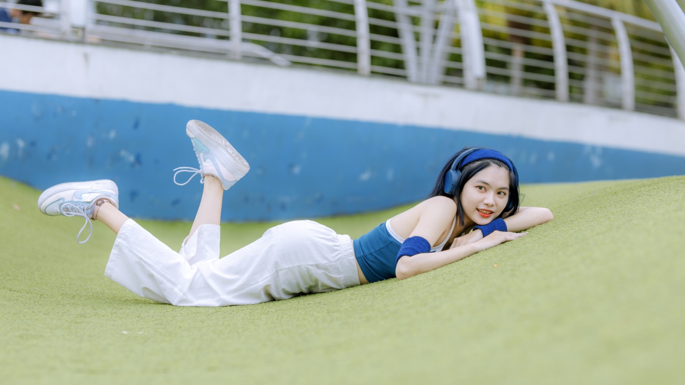 Девушка азиатка в наушниках лежит на полу 