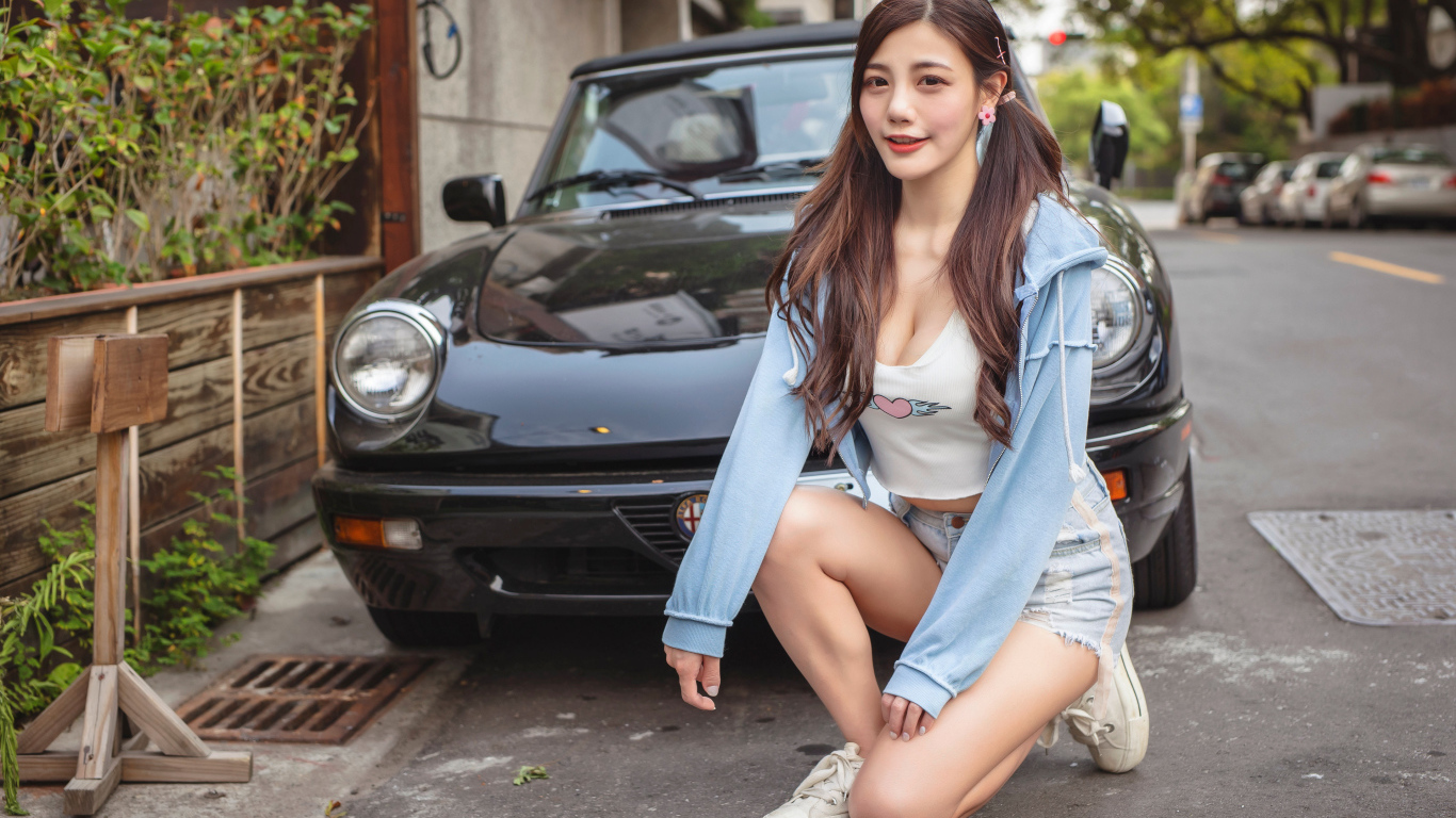 Девушка азиатка сидит возле машины 