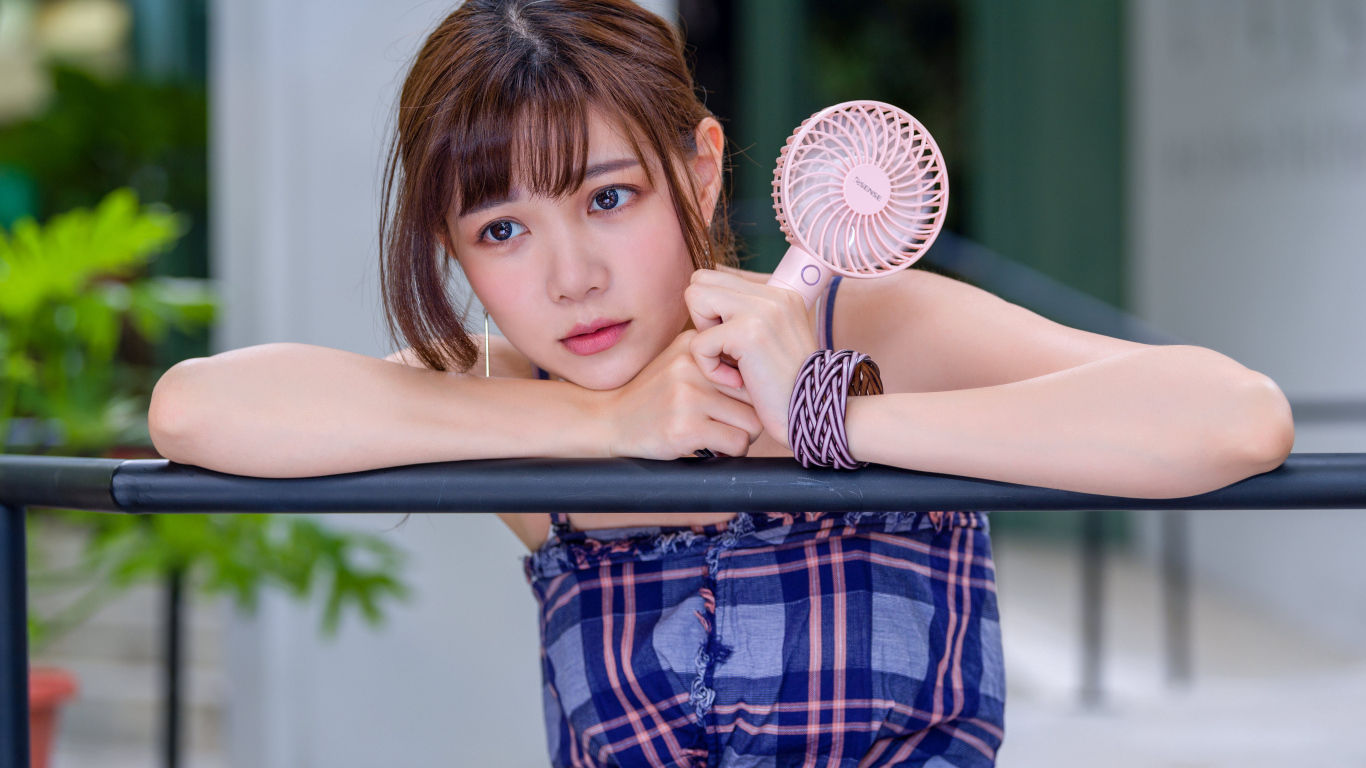 Девушка азиатка с вентилятором в руке 