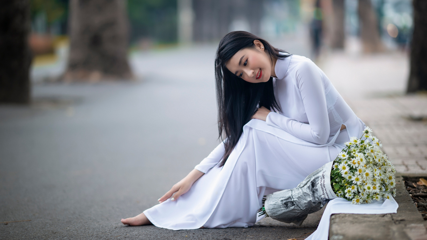 Красивая девушка азиатка в белом платье с букетом ромашек