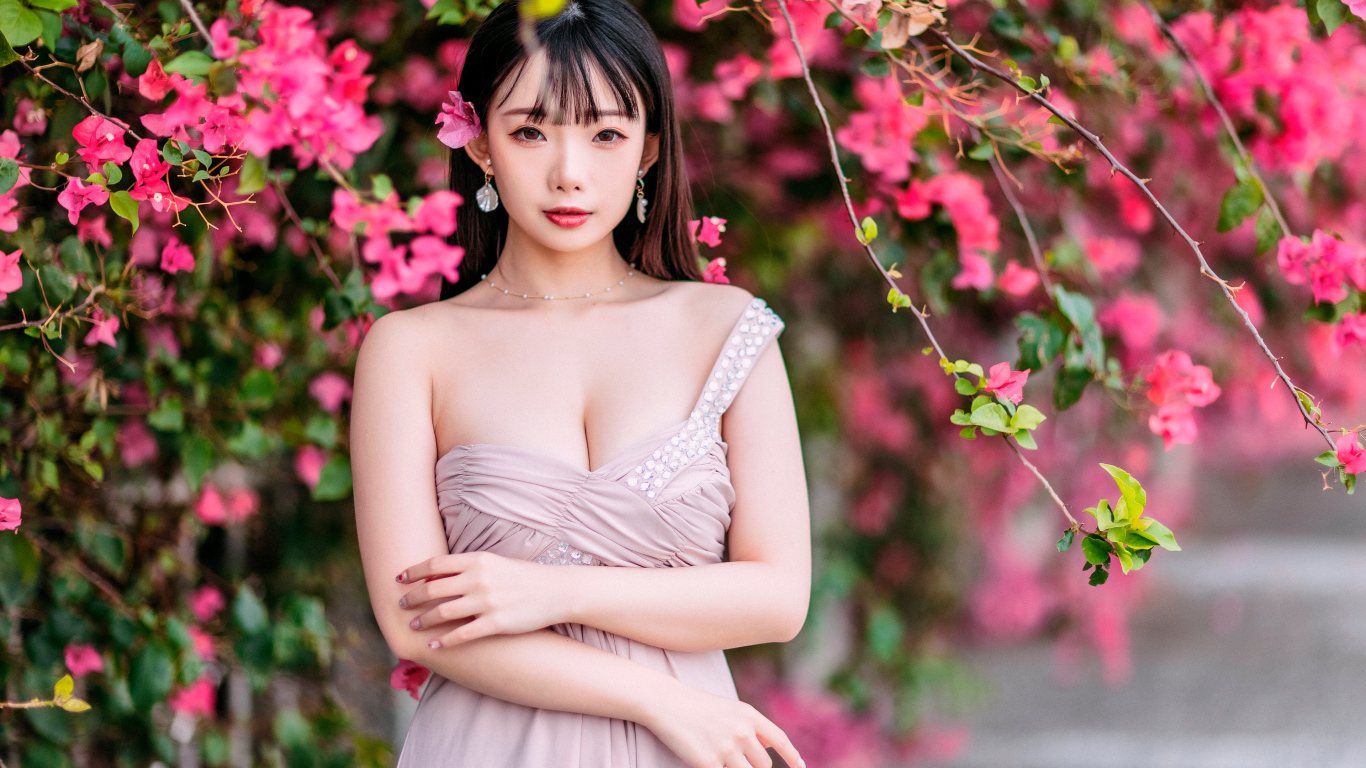 Красивая девушка азиатка у куста с  красными цветами 