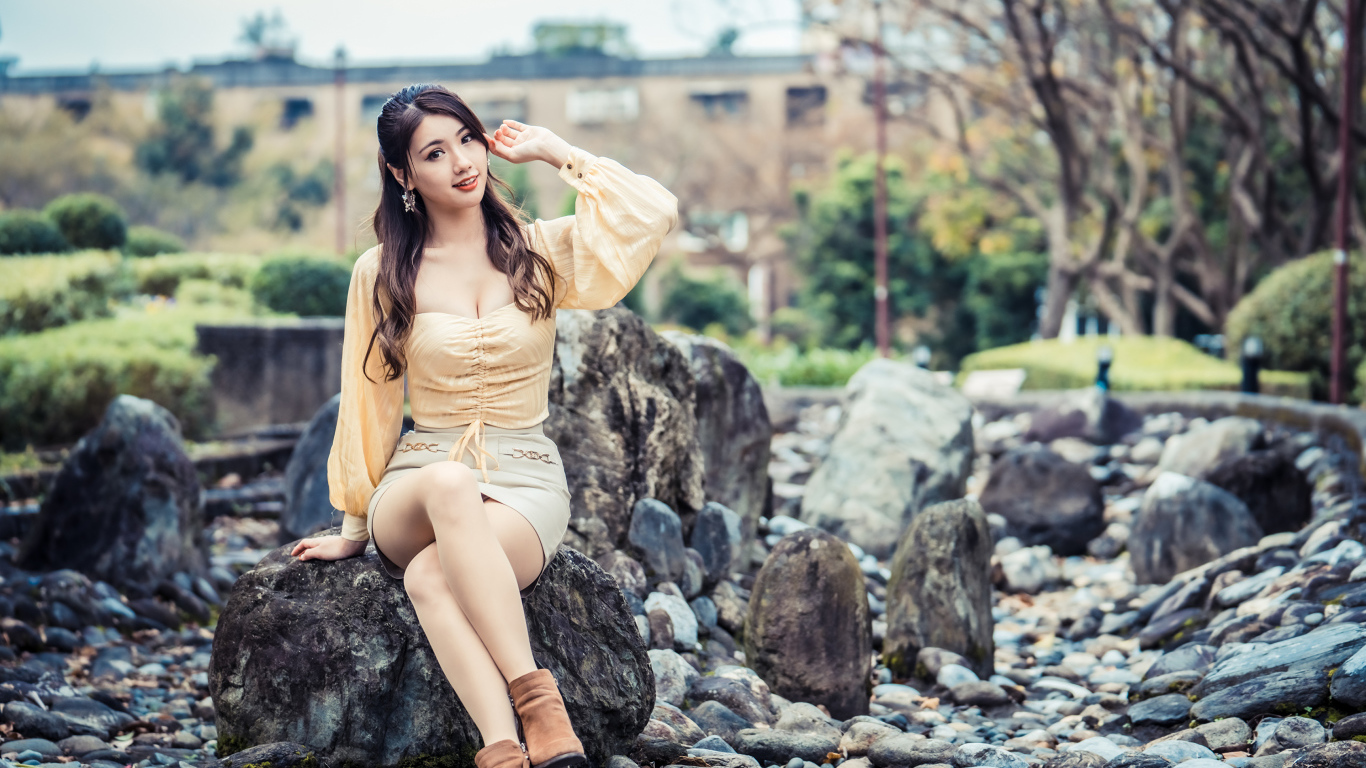Красивая девушка азиатка сидит на камне