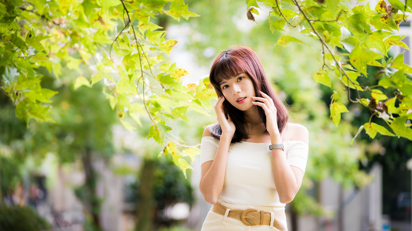 Красивая азиатка в белом платье у дерева 