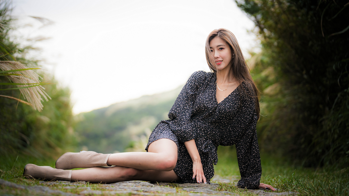 Красивая девушка азиатка в платье лежит на земле 