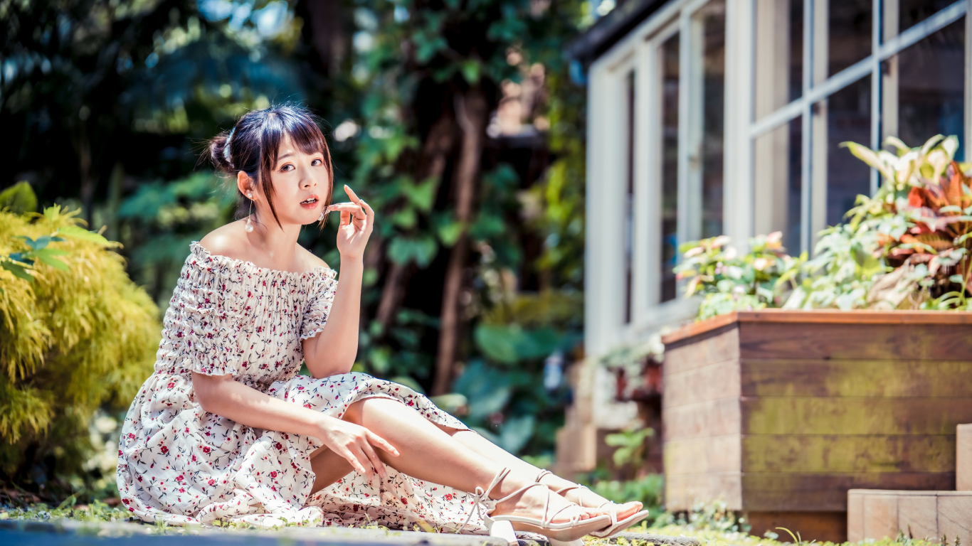 Красивая девушка азиатка в платье сидит на земле