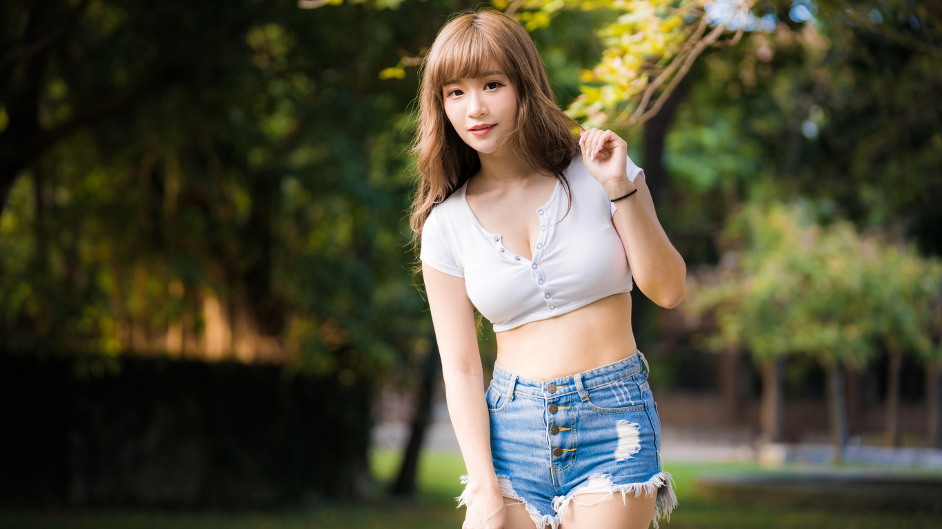 Красивая девушка азиатка в синих джинсах в парке