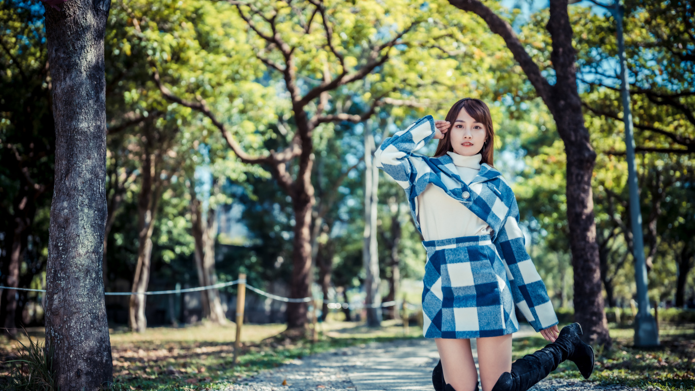 Красивая девушка азиатка стоит на коленях в парке