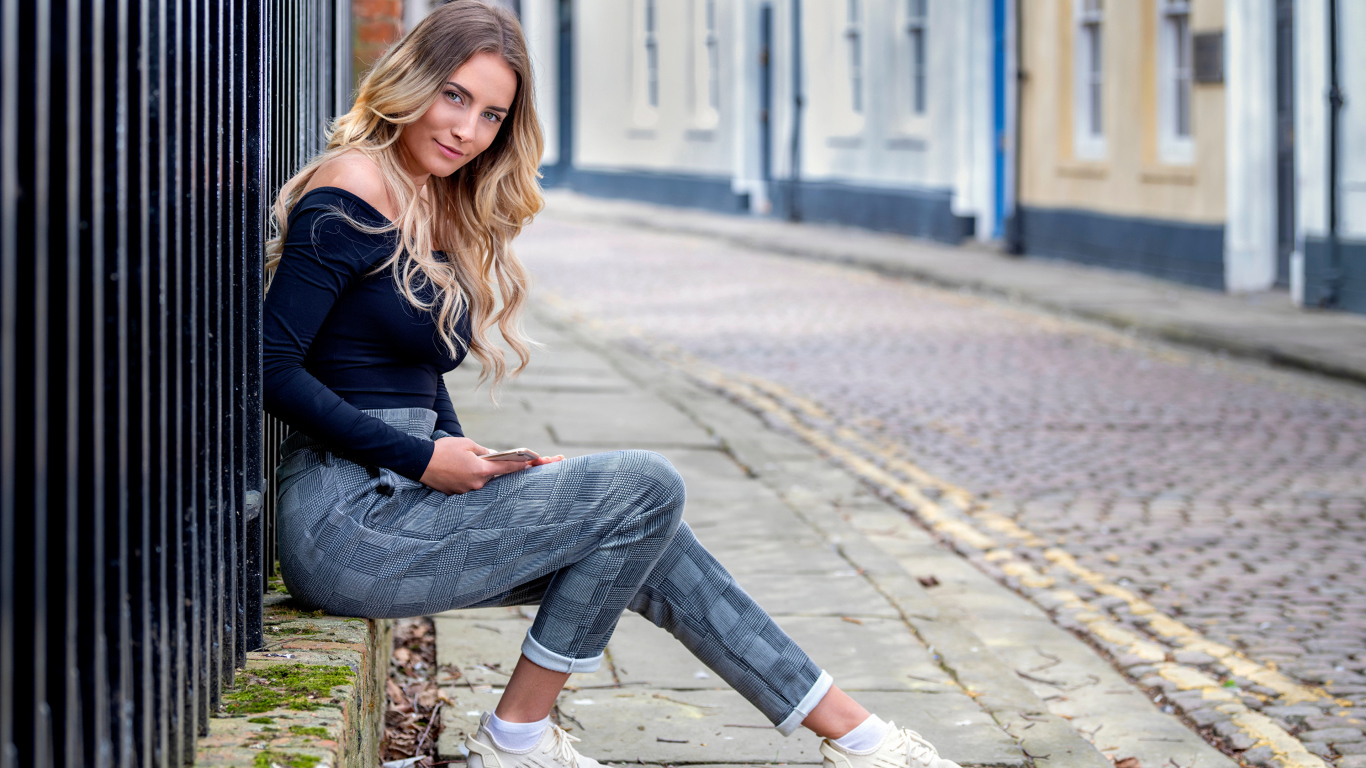 Красивая девушка блондинка сидит у забора