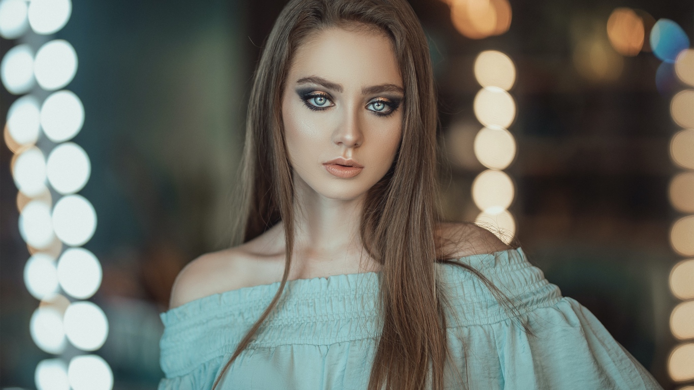 Красивая голубоглазая девушка в платье у зеркала 