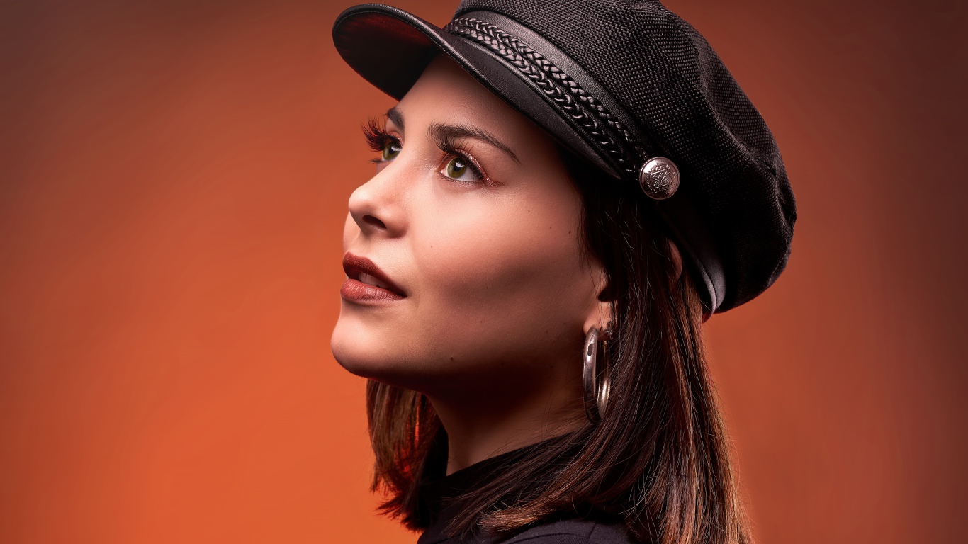 Красивая девушка в кепке на коричневом фоне