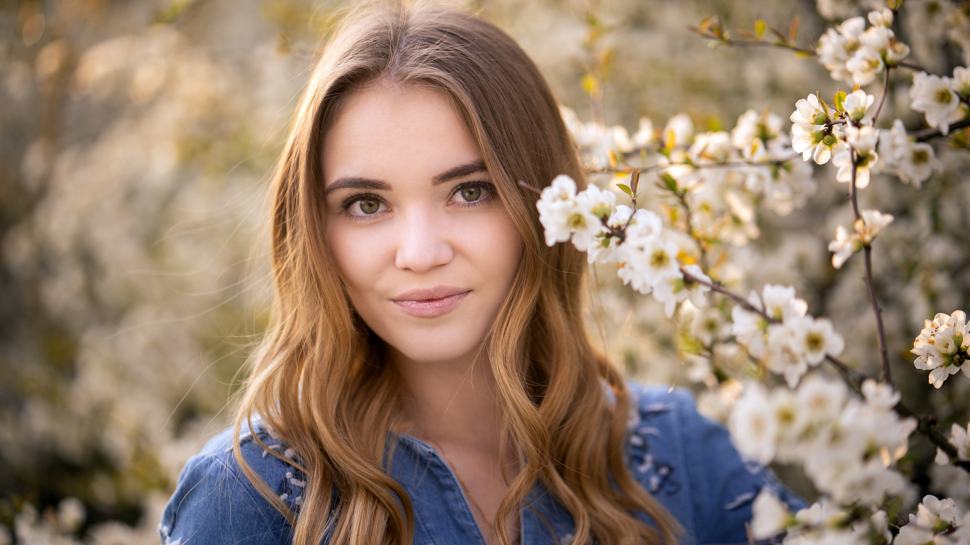 Красивая девушка у ветки с белыми цветами