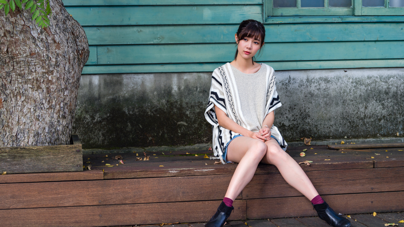 Красивая молодая девушка азиатка сидит у дома