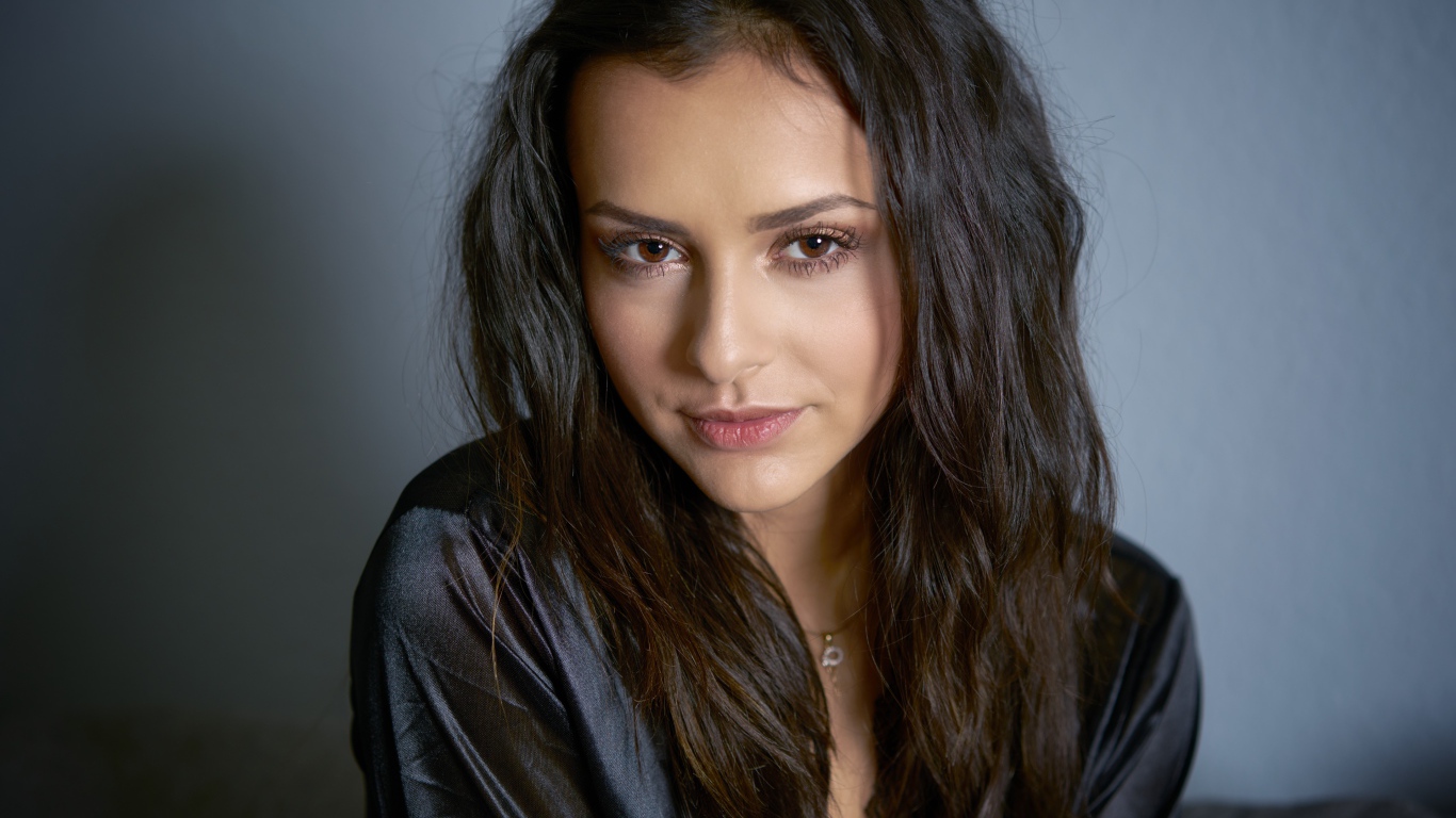 Кареглазая брюнетка в черном халате на сером фоне