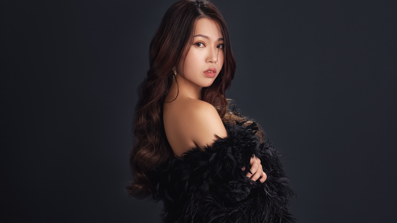 Милая девушка азиатка в черном наряде на сером фоне