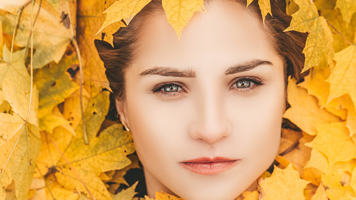 Лицо красивой молодой девушки в желтой листве