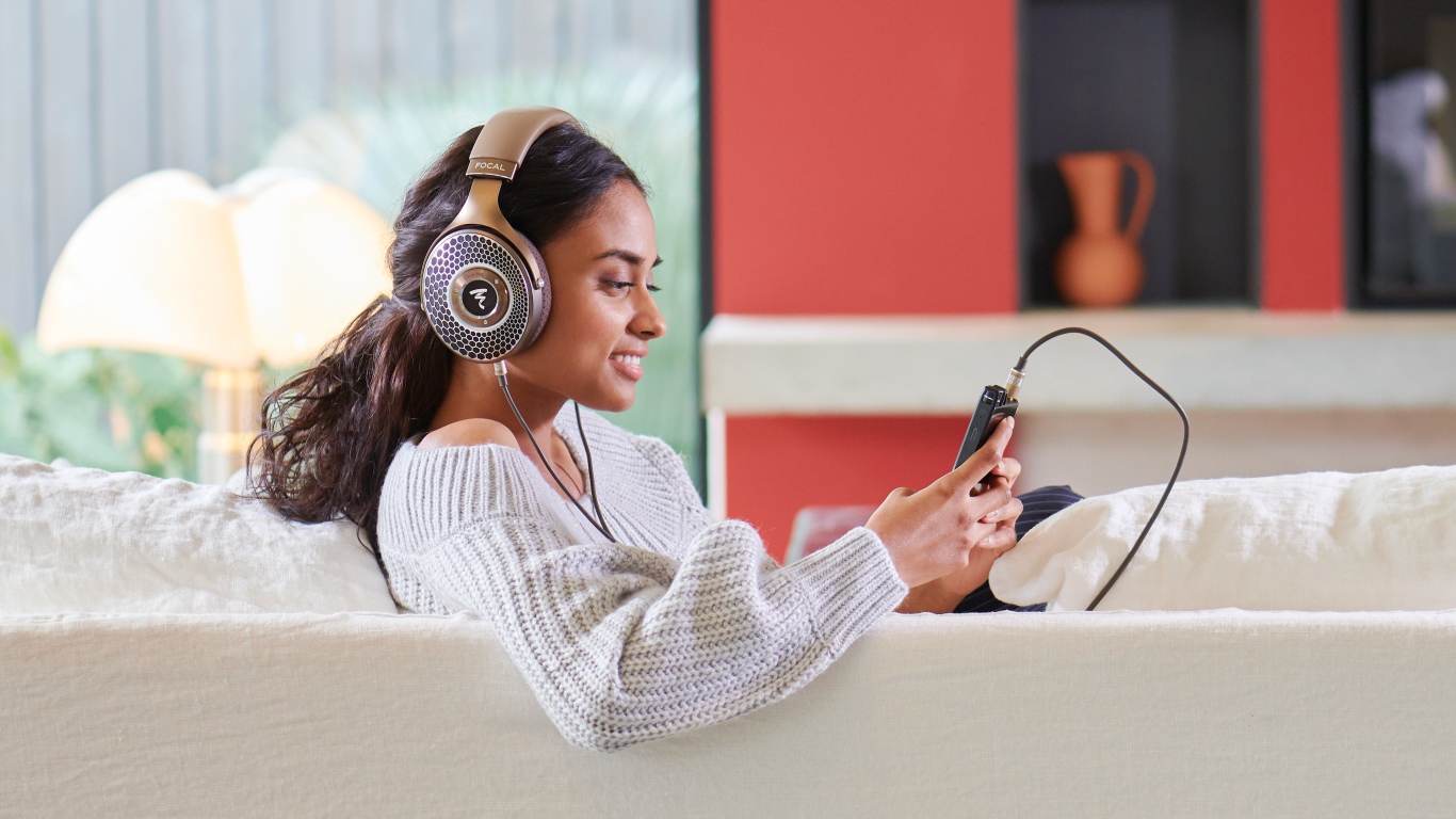 Девушка модель в наушниках на диване с плеером