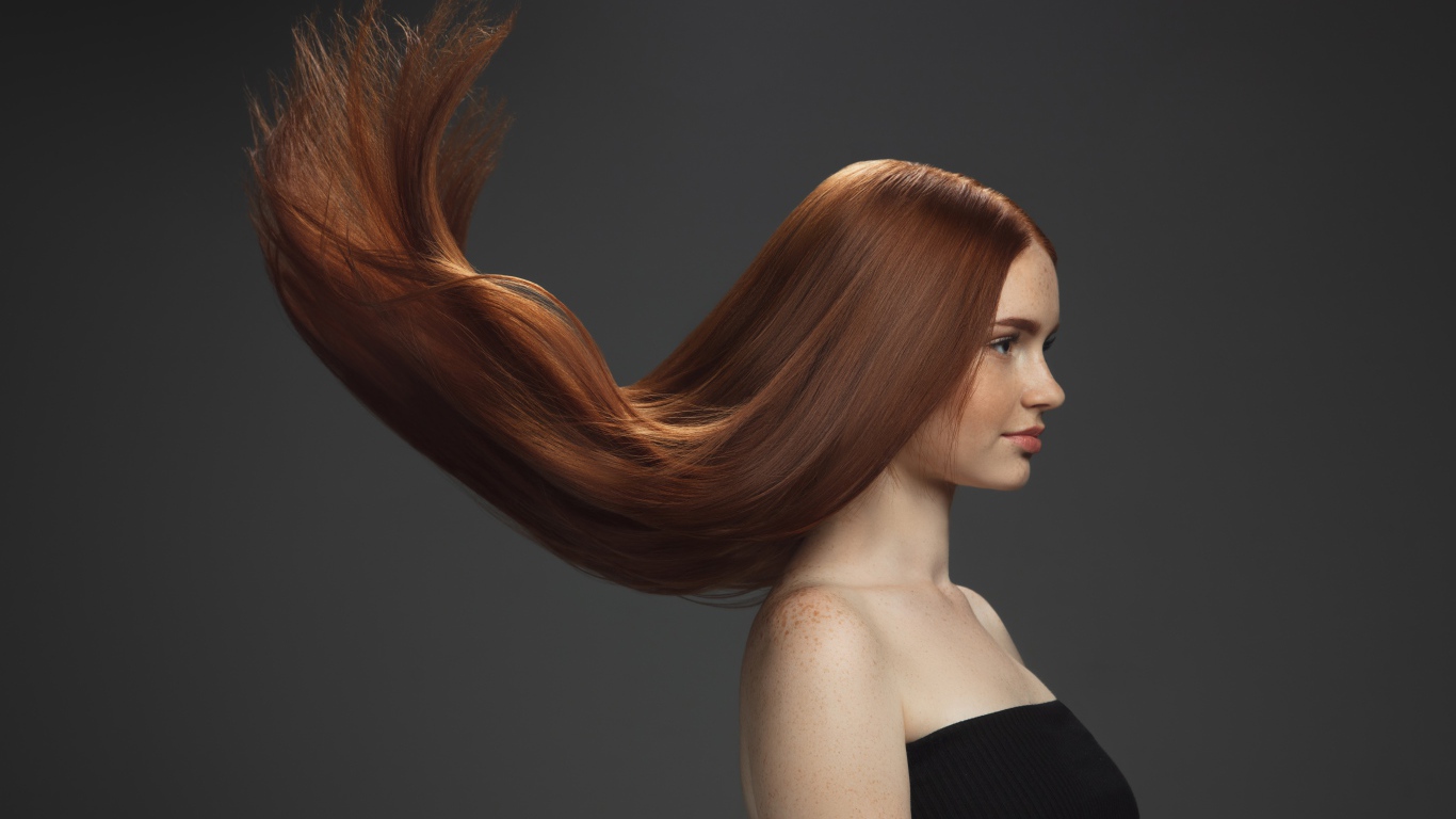 Волосы подняты вверх у красивой девушки на сером фоне