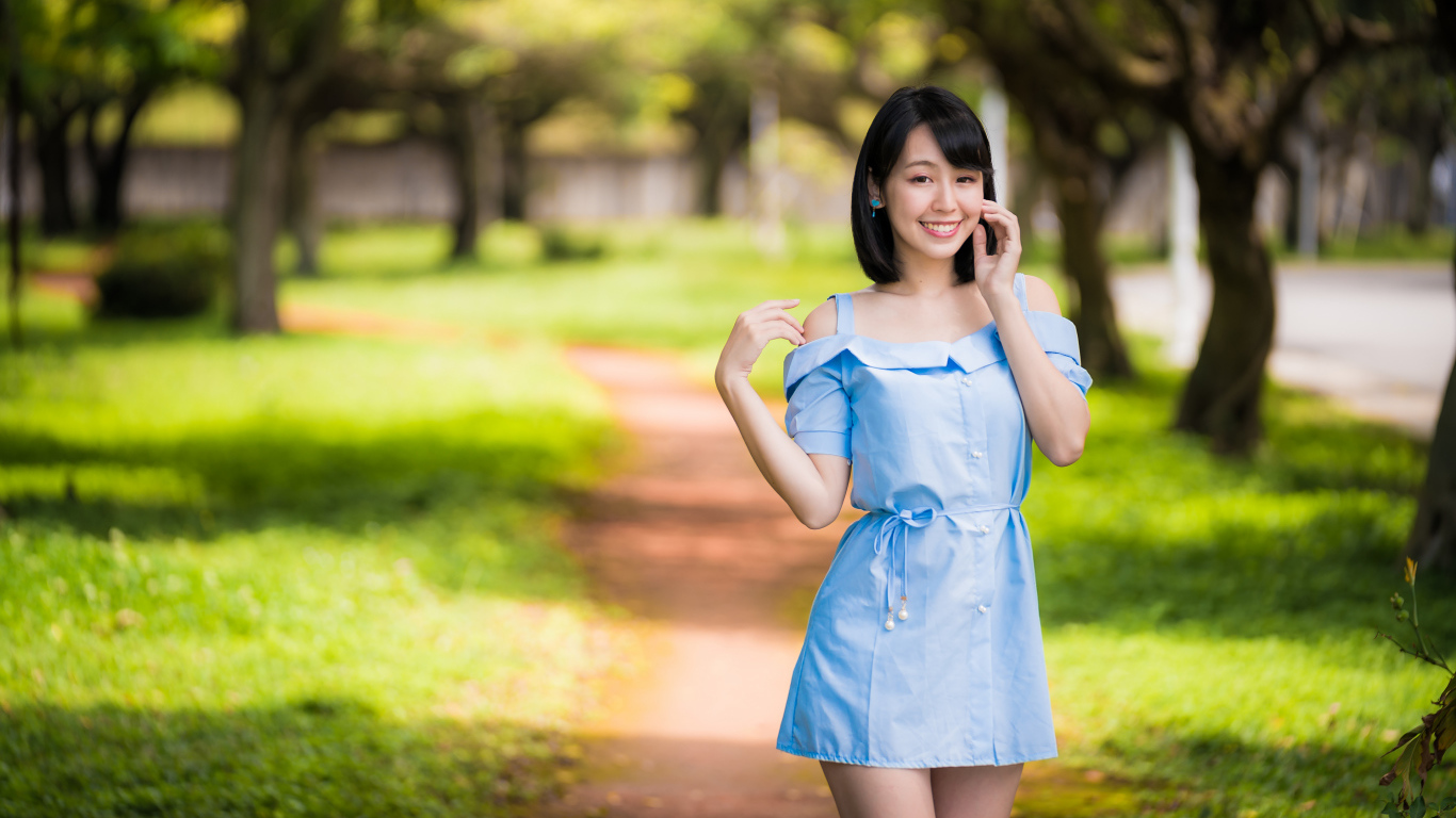 Улыбающаяся девушка азиатка в голубом платье  в парке