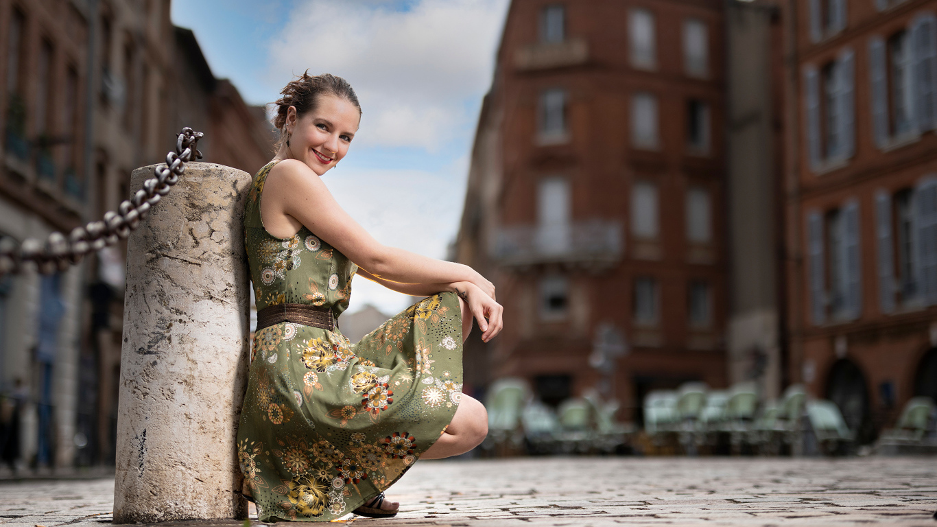 Улыбающаяся девушка в платье на улице города