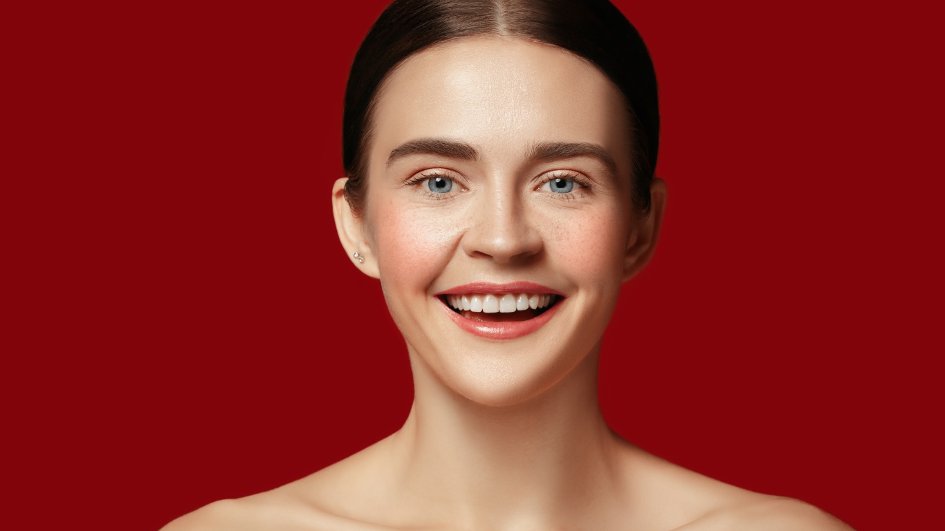 Улыбающаяся молодая девушка на красном фоне