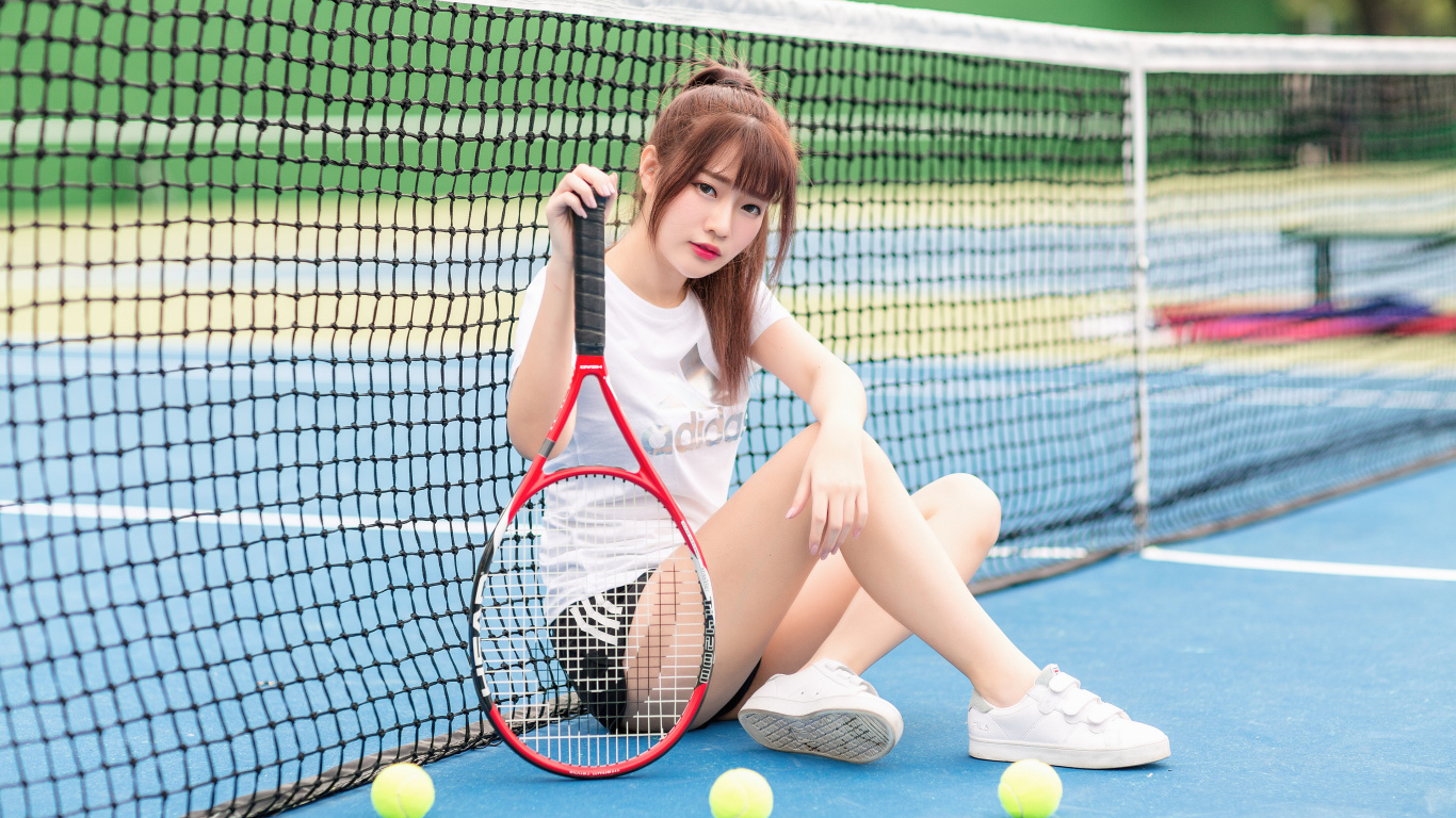 Молодая девушка азиатка с ракеткой на корте