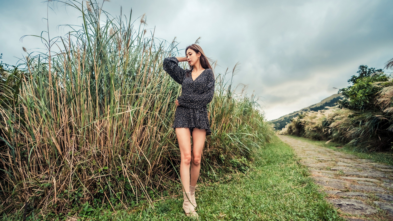 Молодая девушка азиатка стоит у зеленой травы
