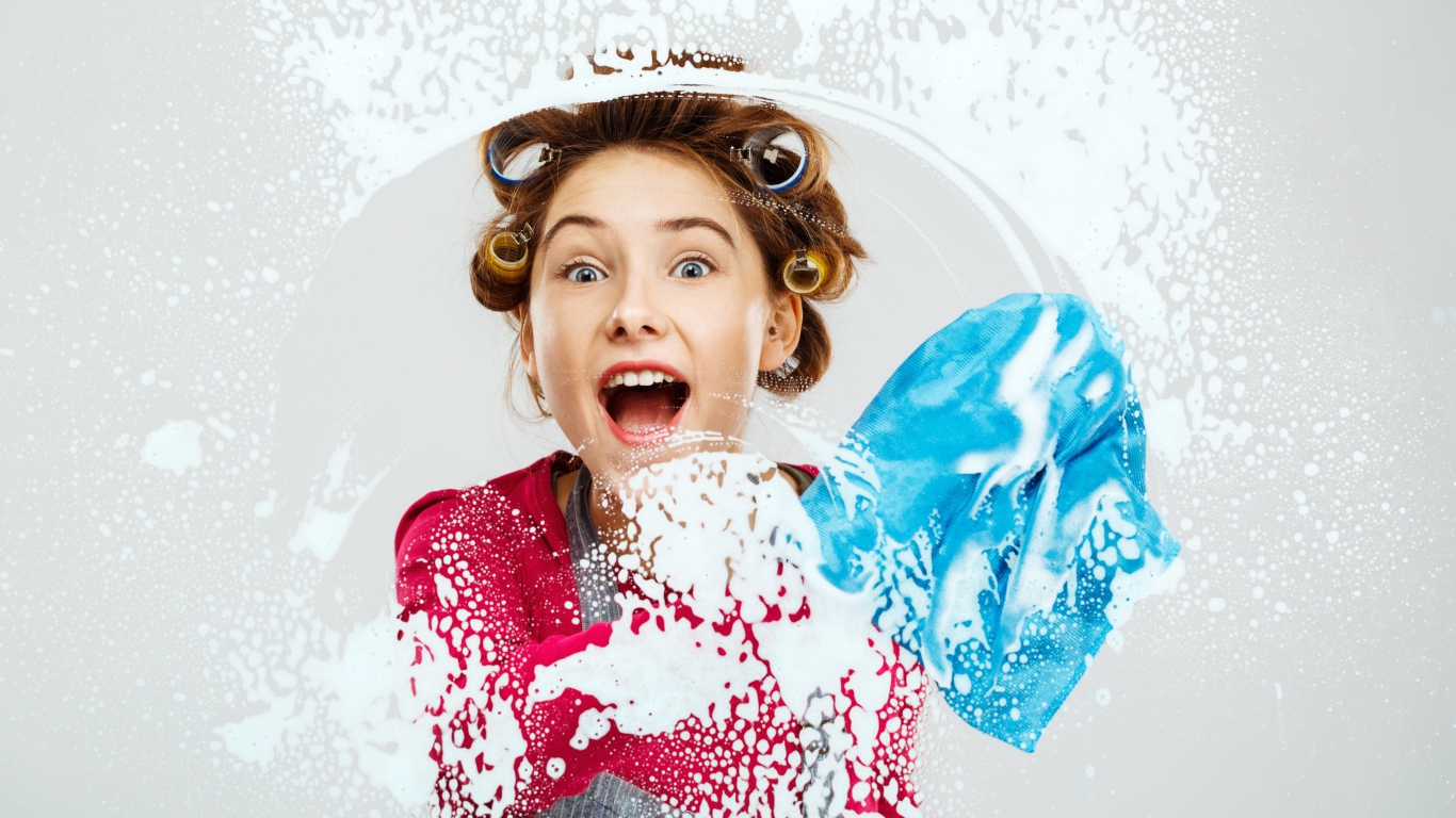 Молодая девушка в бигудях моет окно