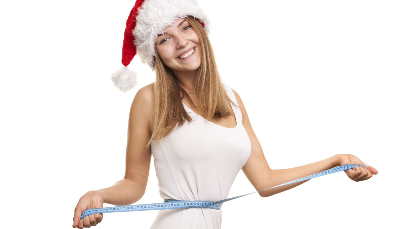 Стройная девушка в новогодней шапке на белом фоне