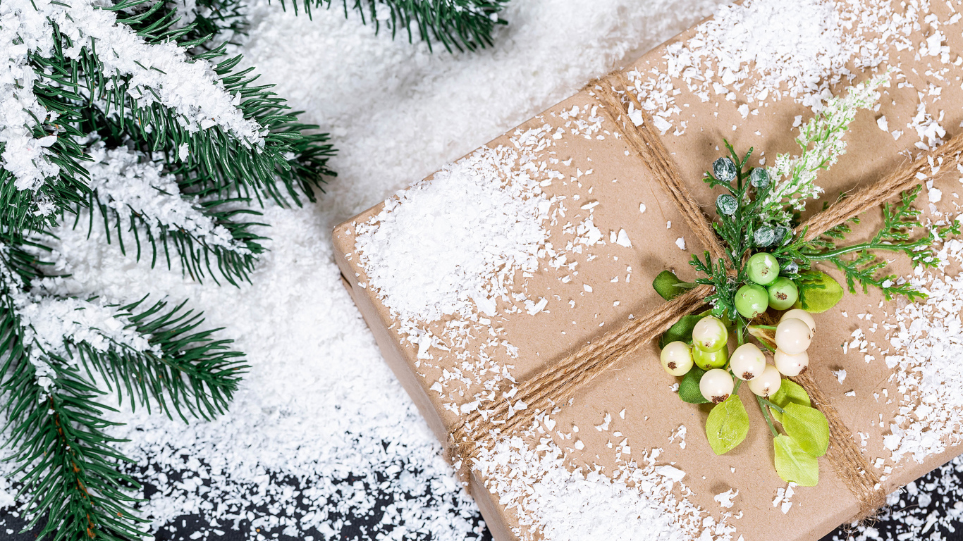 Подарок с заснеженной веткой ели на столе