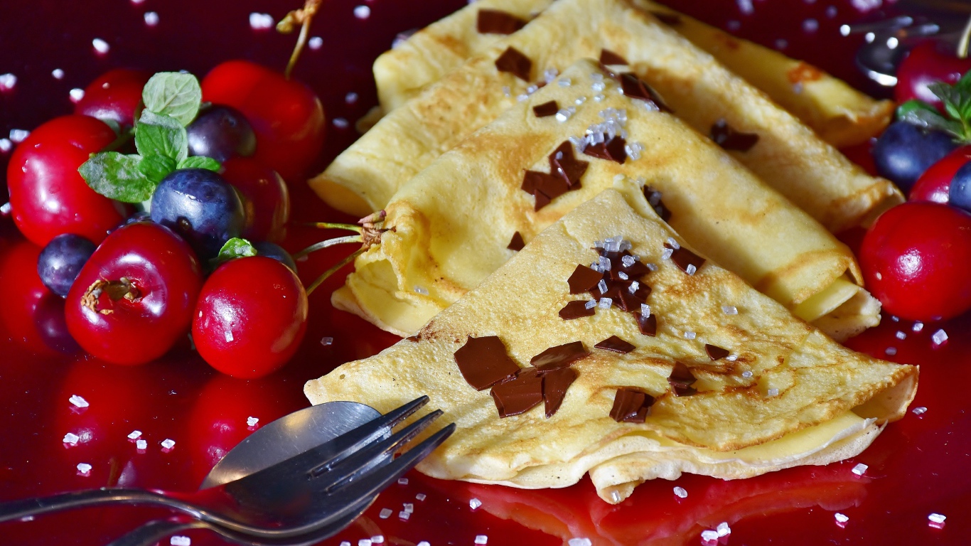 Тонкие блинчики с вишней и черникой на красном фоне масленице