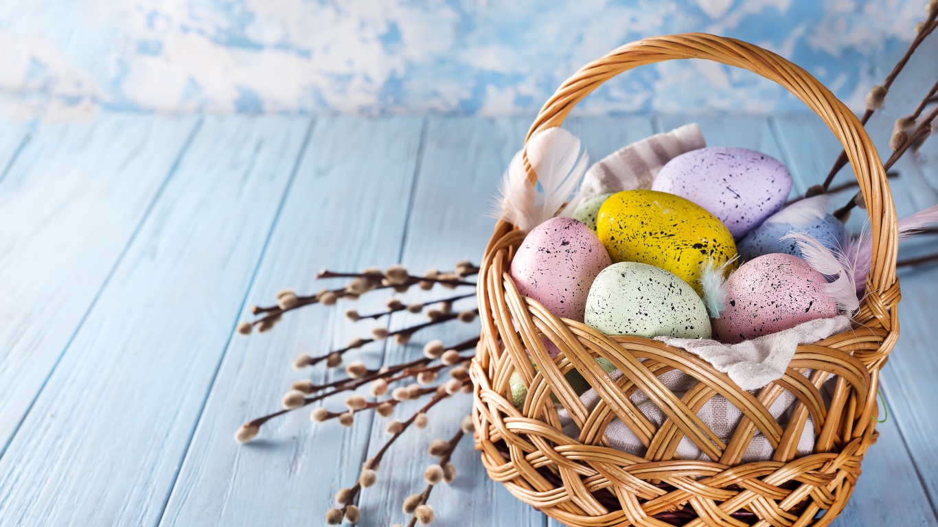 Корзина разноцветных крашеных яиц с ветками вербы на Пасху 2021 