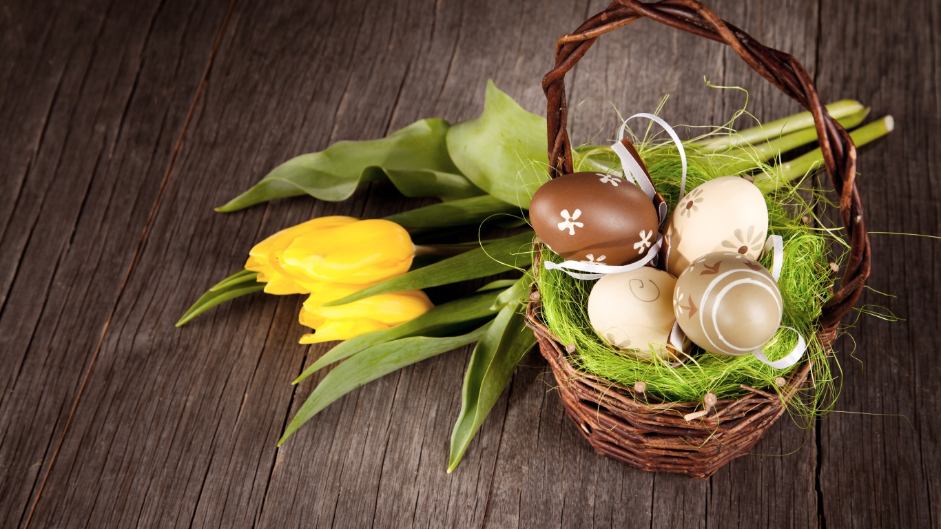 Маленькая корзина с пасхальными  яйцами на столе с тюльпанами
