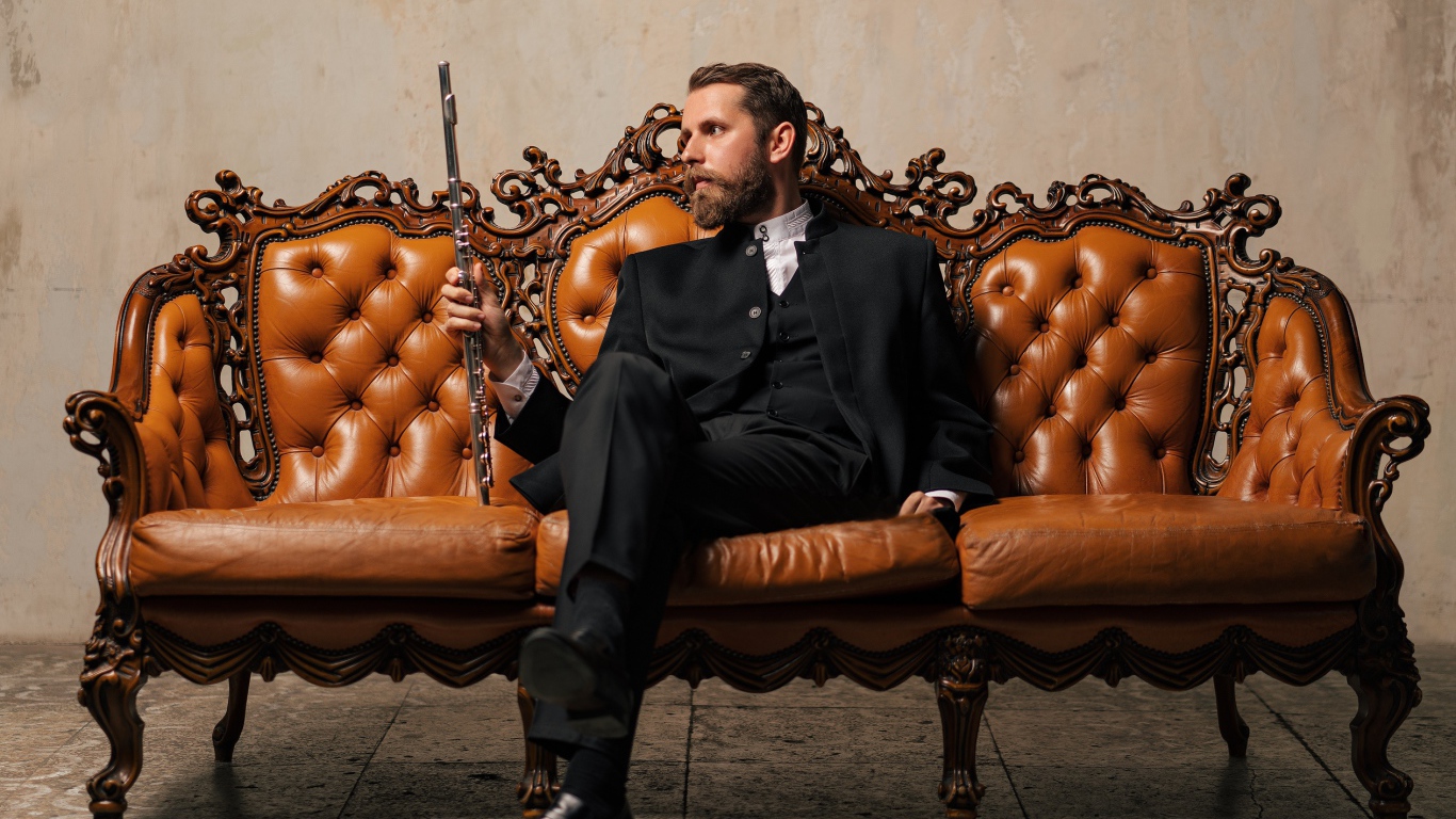 Солидный мужчина в костюме сидит на диване