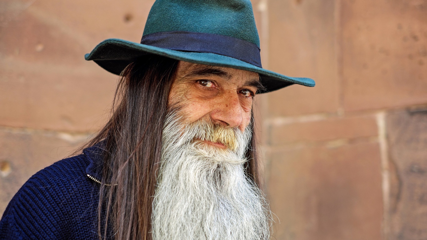 Пожилой мужчина с длинными волосами в шляпе 