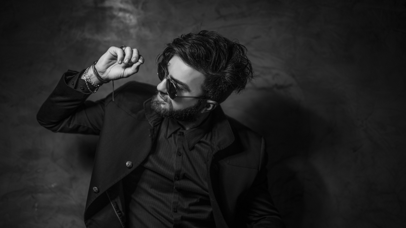 Мужчина в черном костюме на фоне стены