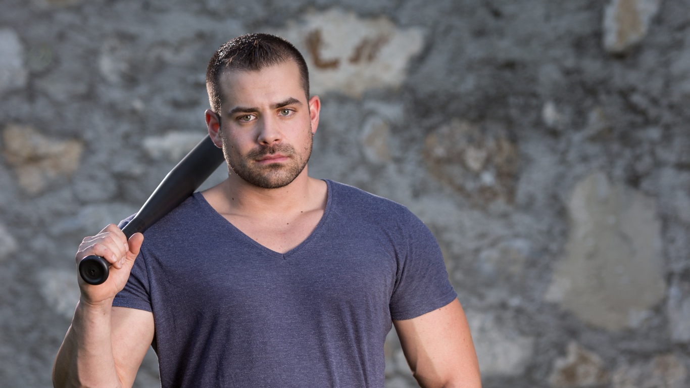 Серьезный парень с бейсбольной битой в руке 