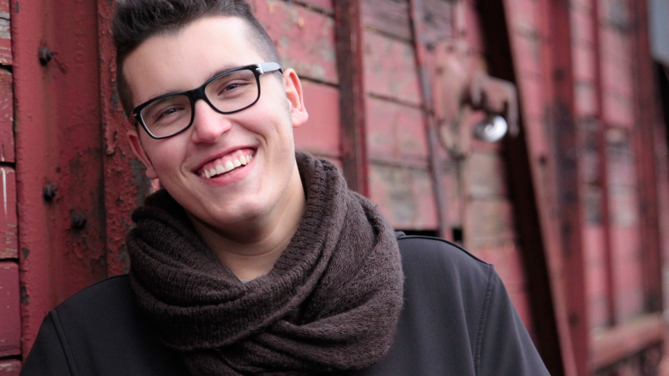 Улыбающийся мужчина в очках у стены 