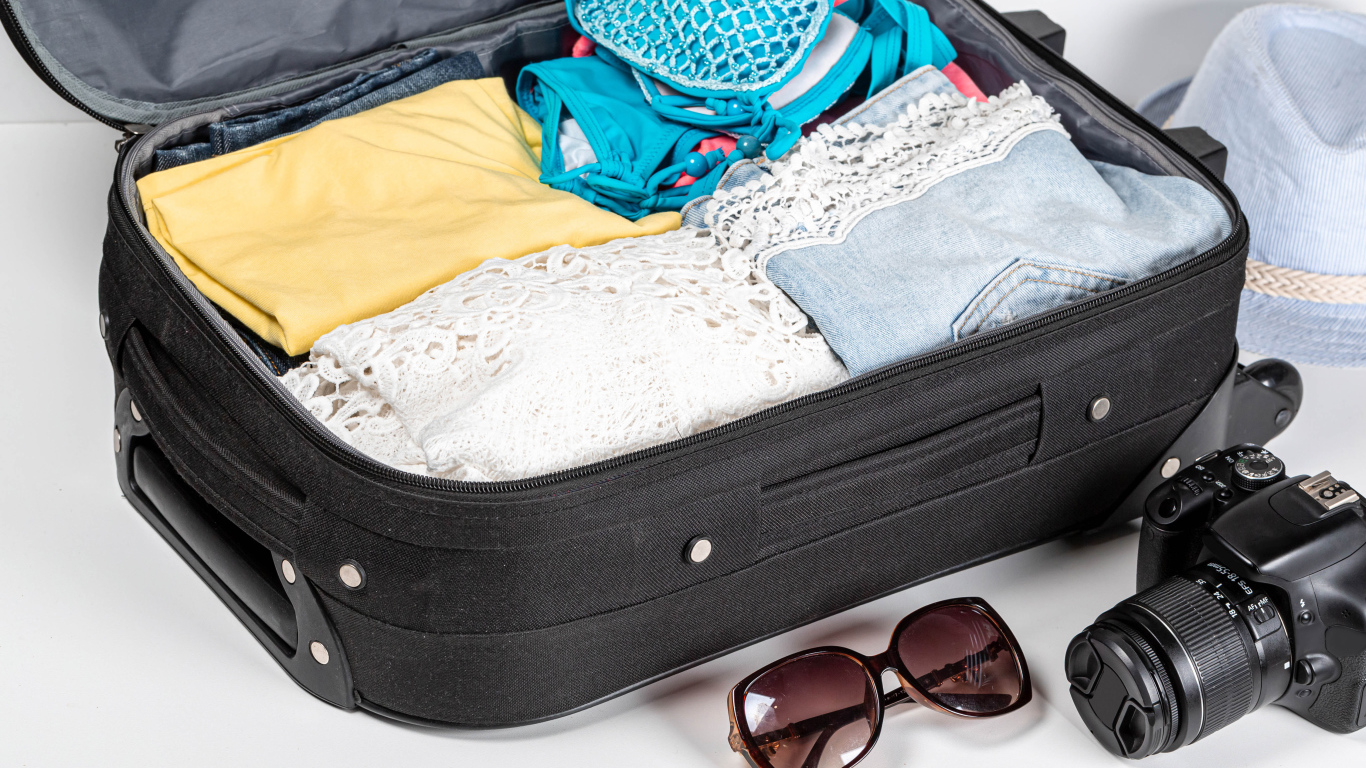 Чемодан с вещами для отпуска с фотоаппаратом и очками 