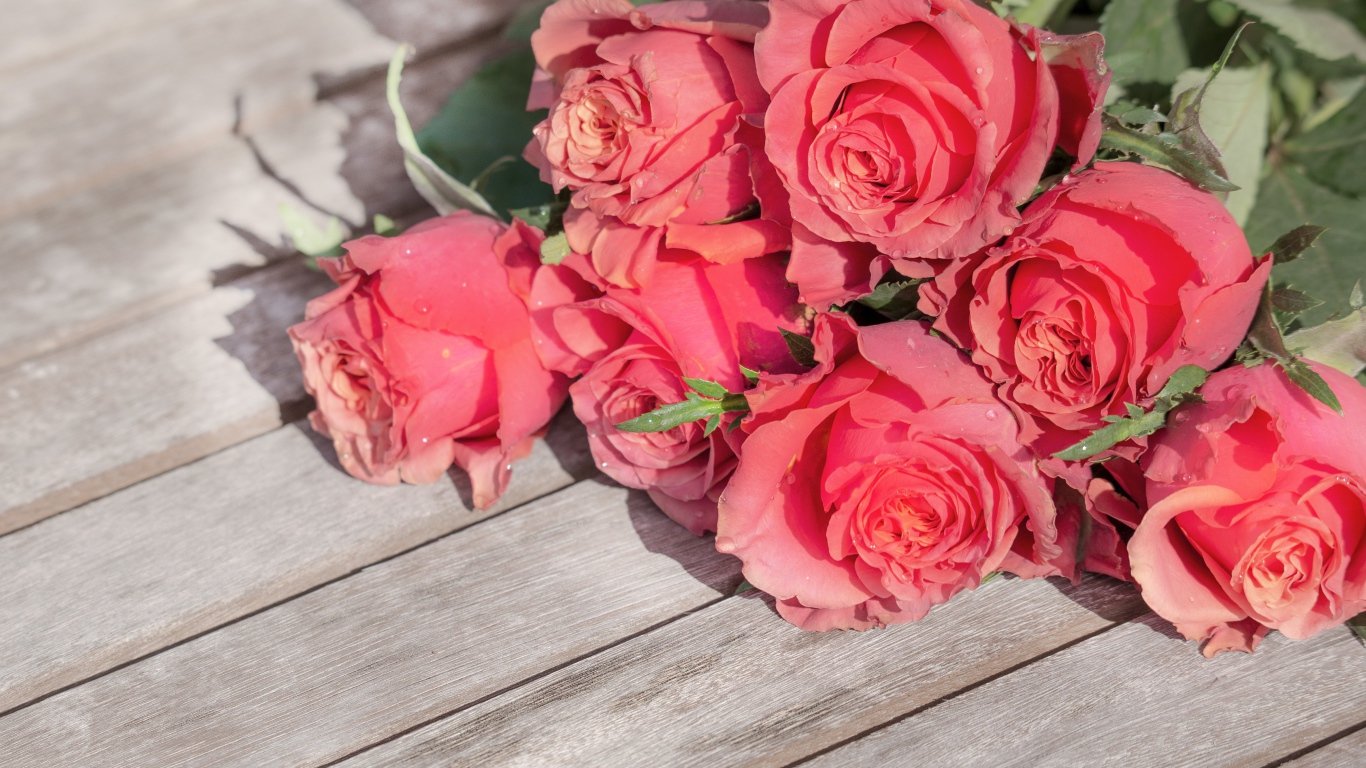 Букет розовых роз лежит на деревянном столе