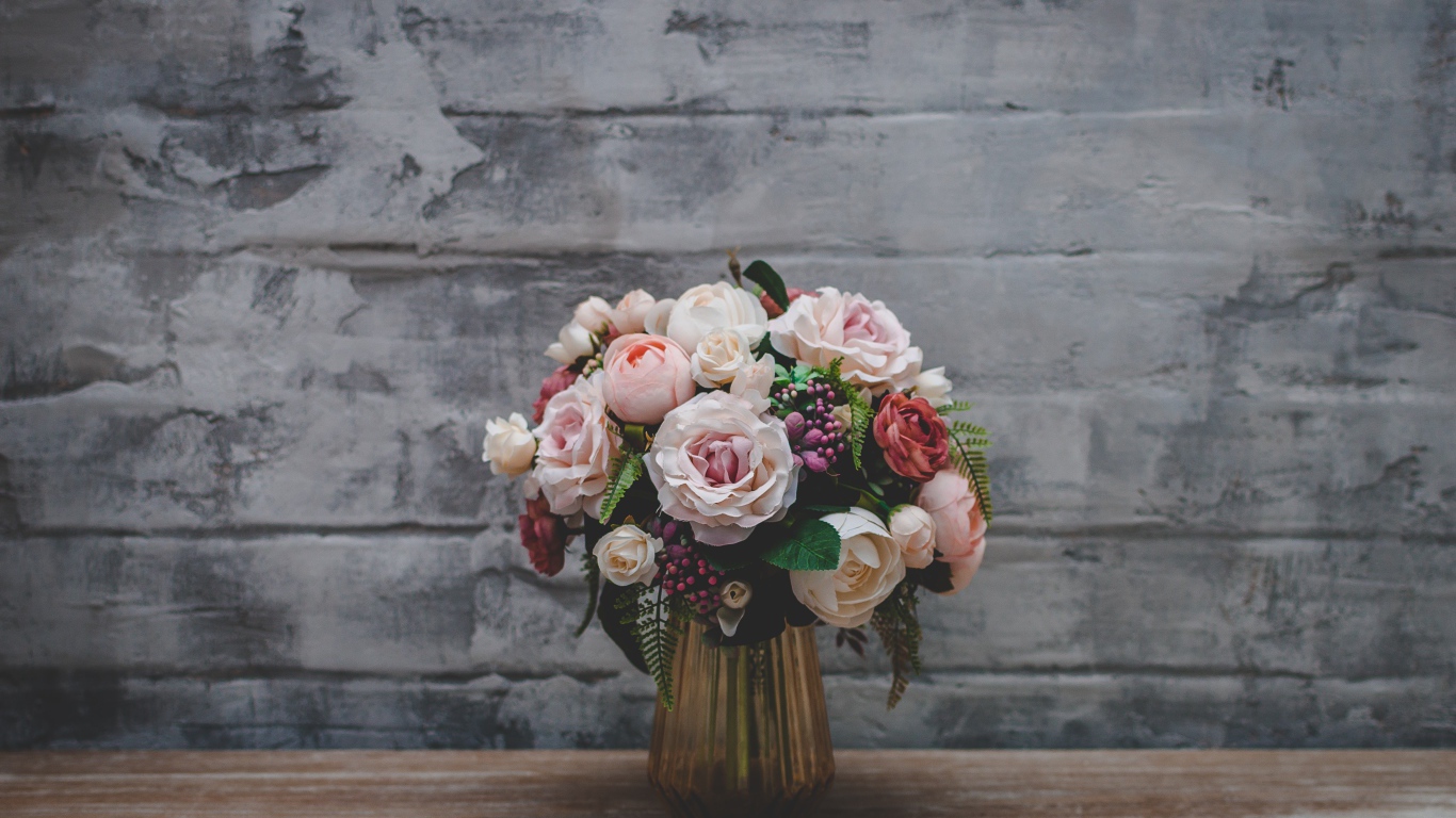 Розовый букет роз  стоит у серой стены 