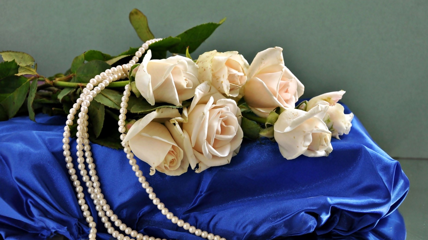 Букет белых роз с бусами на голубой ткани 