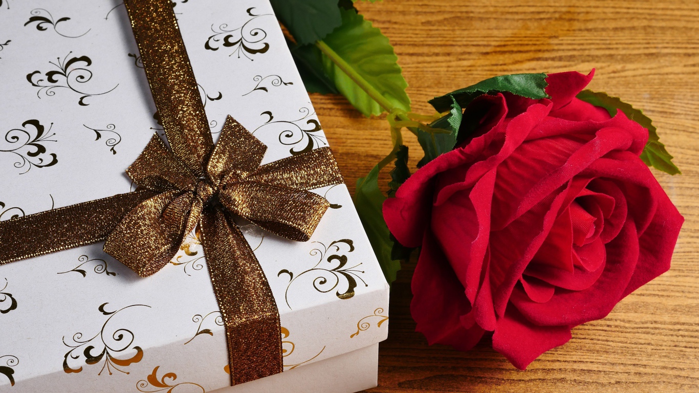 Красный цветок розы на столе с подарком